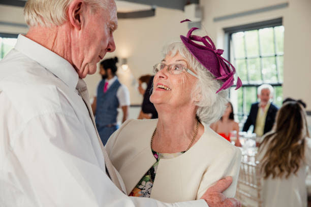 Senior couple are sharing a dance at a wedding. They are looking lovingly at each other while they dance.