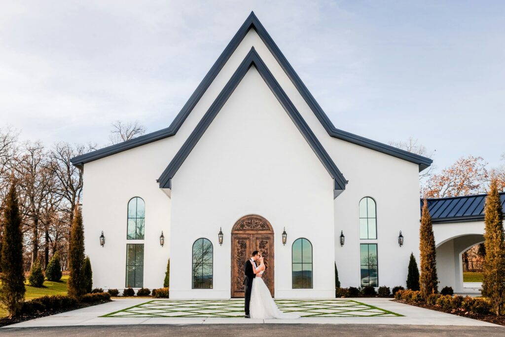 Bride and groom kissing in front of a white chapel