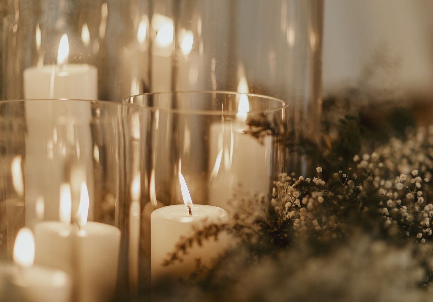 Candles glowing within elegant glass jars lined up in a row.