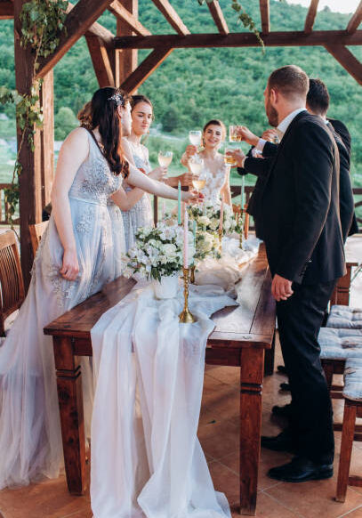 Boho style wedding party. Banquet with friends, bride and groom outdoors.